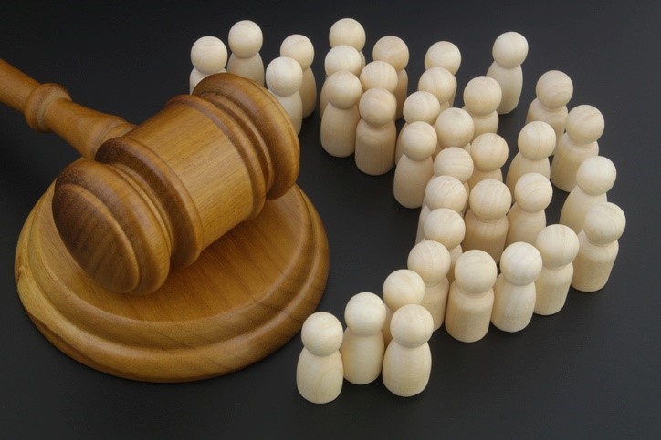 A gavel sits beside wooden figures representing a class-action lawsuit.
